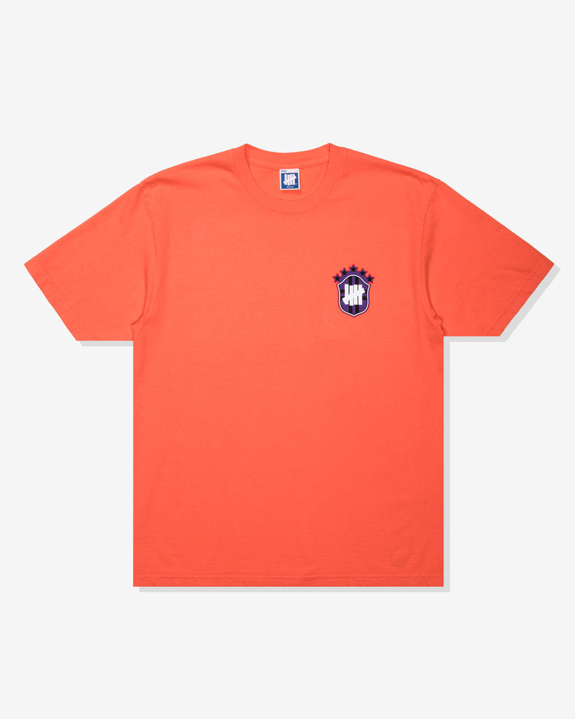 UNDEFEATED SP26 EMBLEM S/S TEE-CORAL