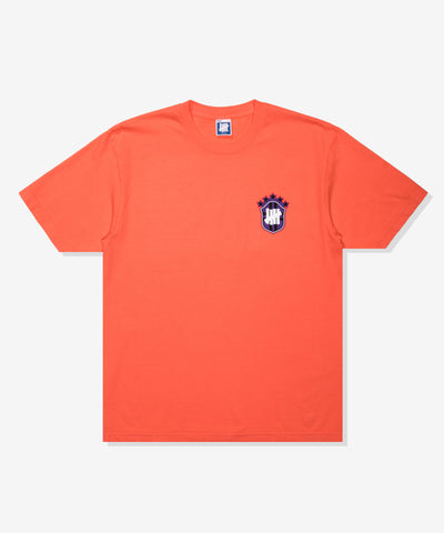 UNDEFEATED SP26 EMBLEM S/S TEE-CORAL