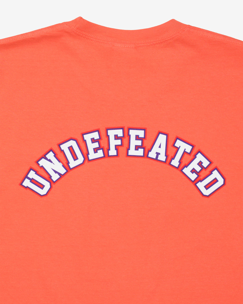 UNDEFEATED SP26 EMBLEM S/S TEE-CORAL