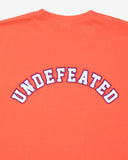 UNDEFEATED SP26 EMBLEM S/S TEE-CORAL